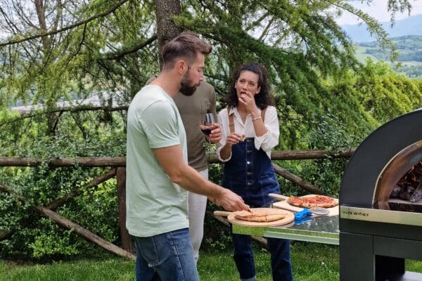 Clementi Gold pizzaoven met Premium onderstel en RVS zijwerkblad tijdens het serveren van pizza