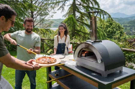 mesnen om de clementino houtoven met een pizza ie net uit de houtoven komt