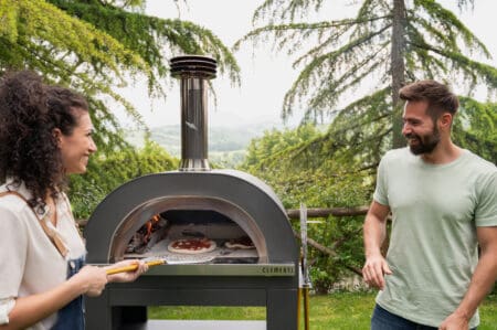 Clementi GOLD Houtoven sfeerbeeld in tuin met mensen die pizza bakken