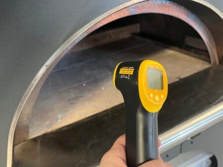 Infraroodthermometer gericht op de stenen ovenvloer van een pizzaoven