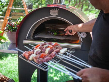 Vleesspiesen en groenten grillen op een rooster in een Clementi pizzaoven