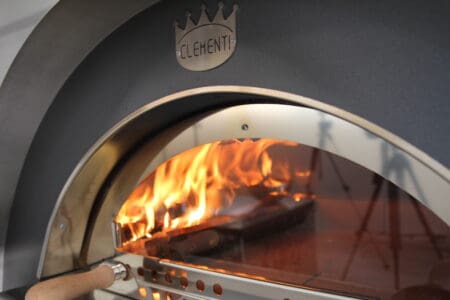 Mooi zicht op brandend vuur in pizzaoven door glazen venster